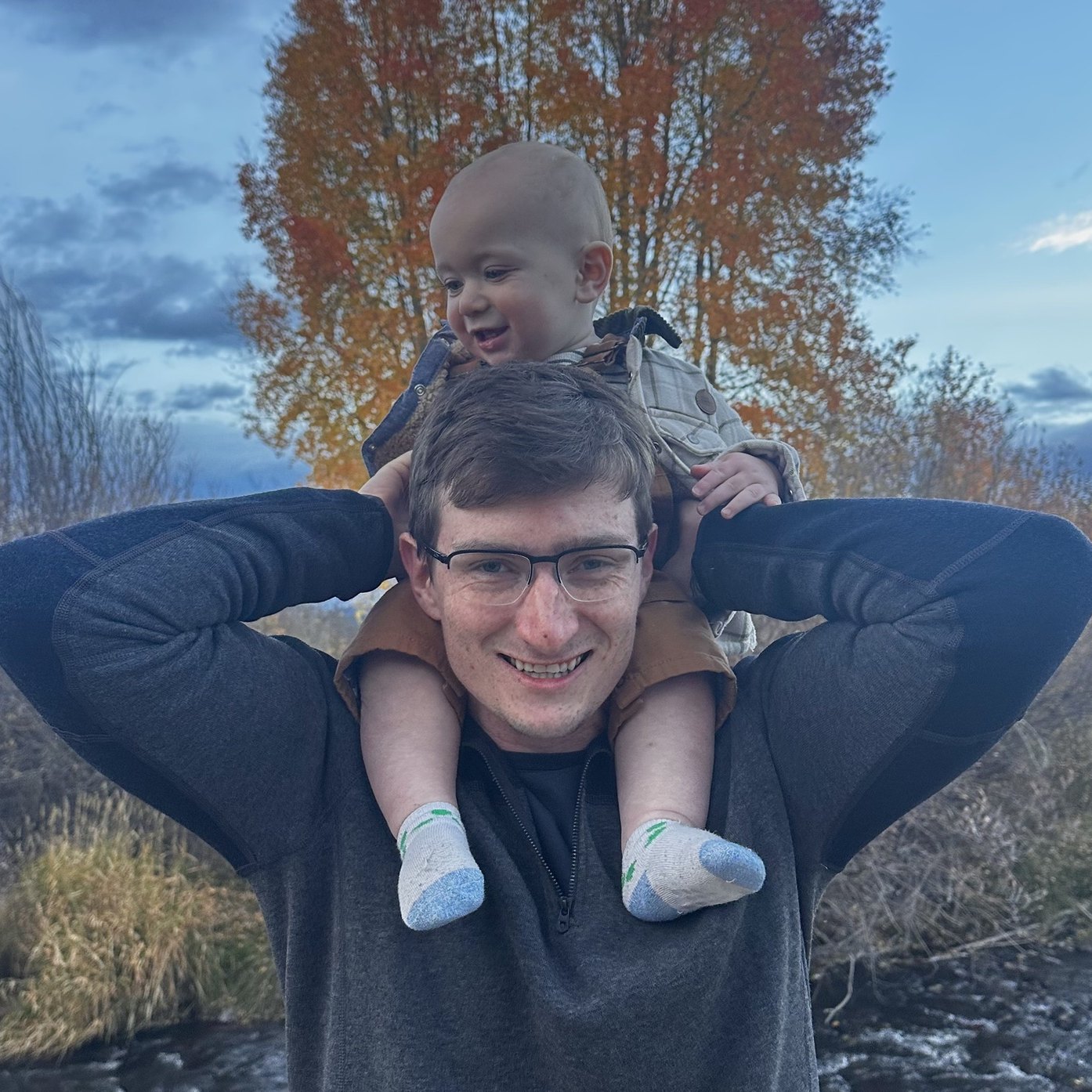 Noah Johnson of Alternative Window Cleaning smiling outdoors with his baby on his shoulders