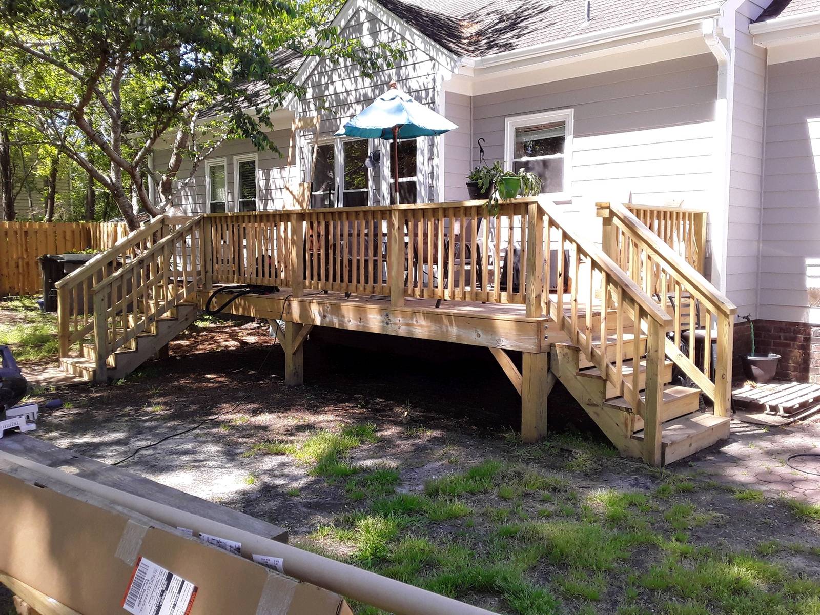 A new wooden deck with two sets of steps and railings on the back of a light gray house