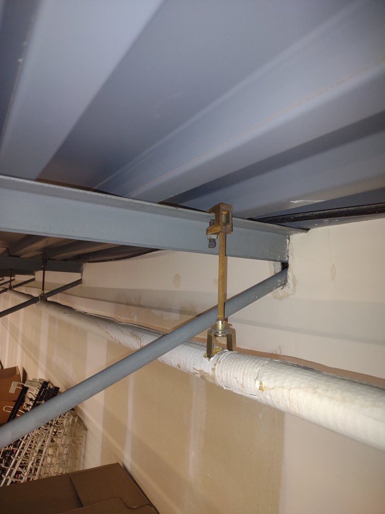 Metal beam and threaded rod hanger supporting an insulated pipe along the ceiling of a storage room