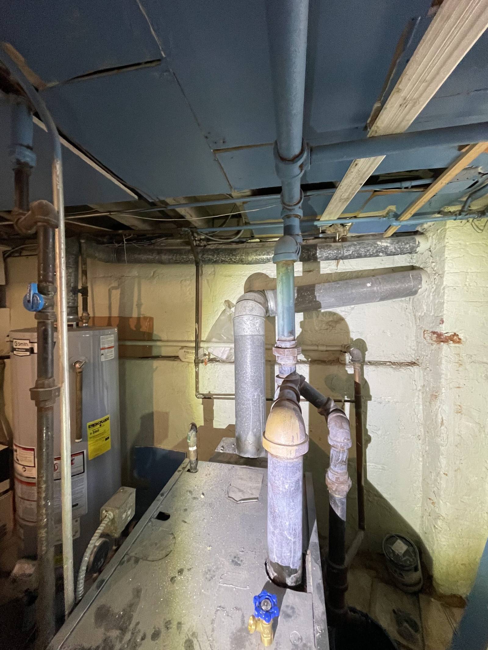 A water heater and a boiler with their vent pipes in a basement
