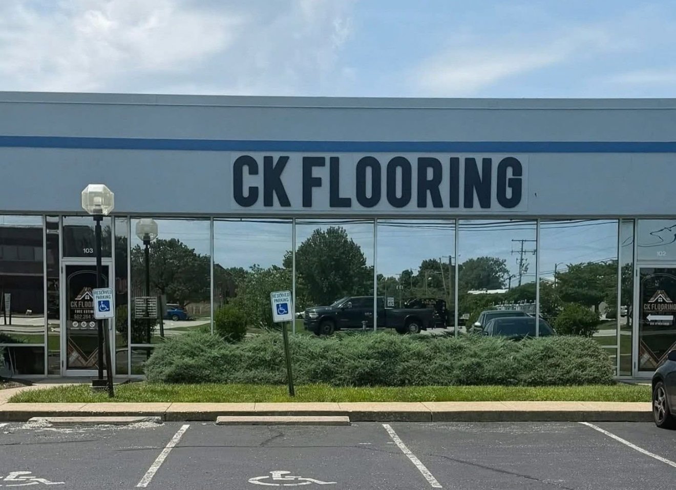The CK Flooring storefront, with the company name in large dark letters above a long glass front and reserved parking spaces in the foreground