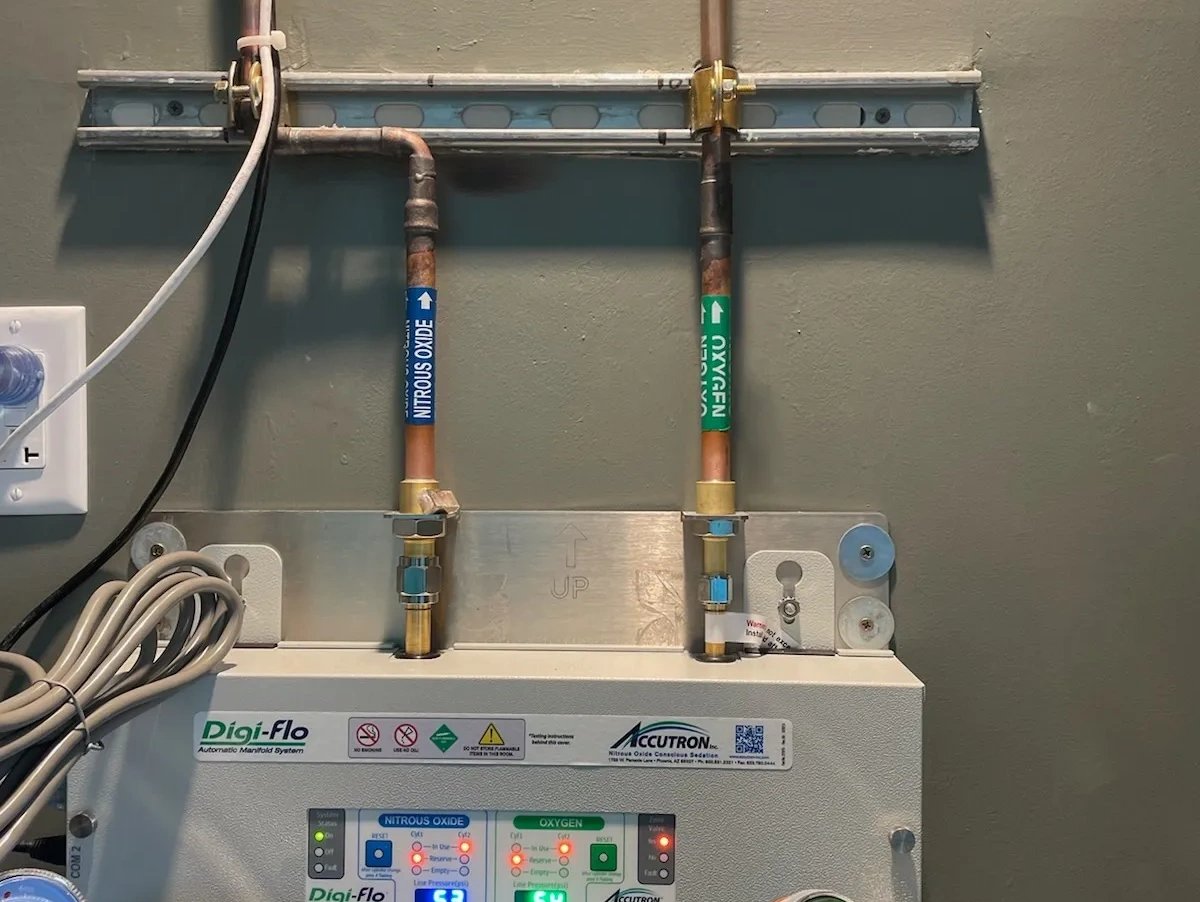Copper nitrous oxide and oxygen medical gas lines with labeled pipe markers above a Digi-Flo automatic manifold control panel