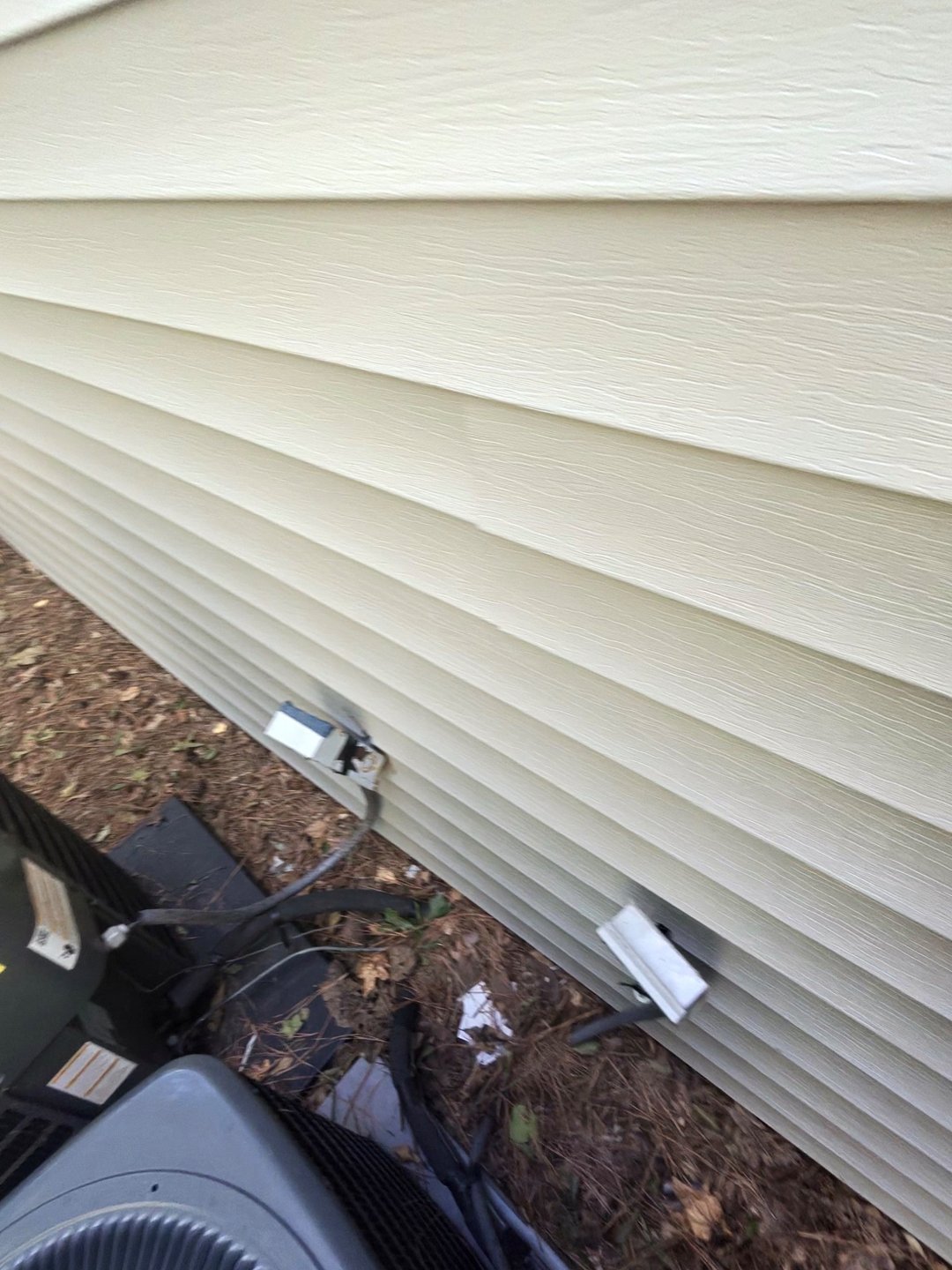 Disconnect boxes and wiring on the vinyl siding beside an outdoor air-conditioning unit