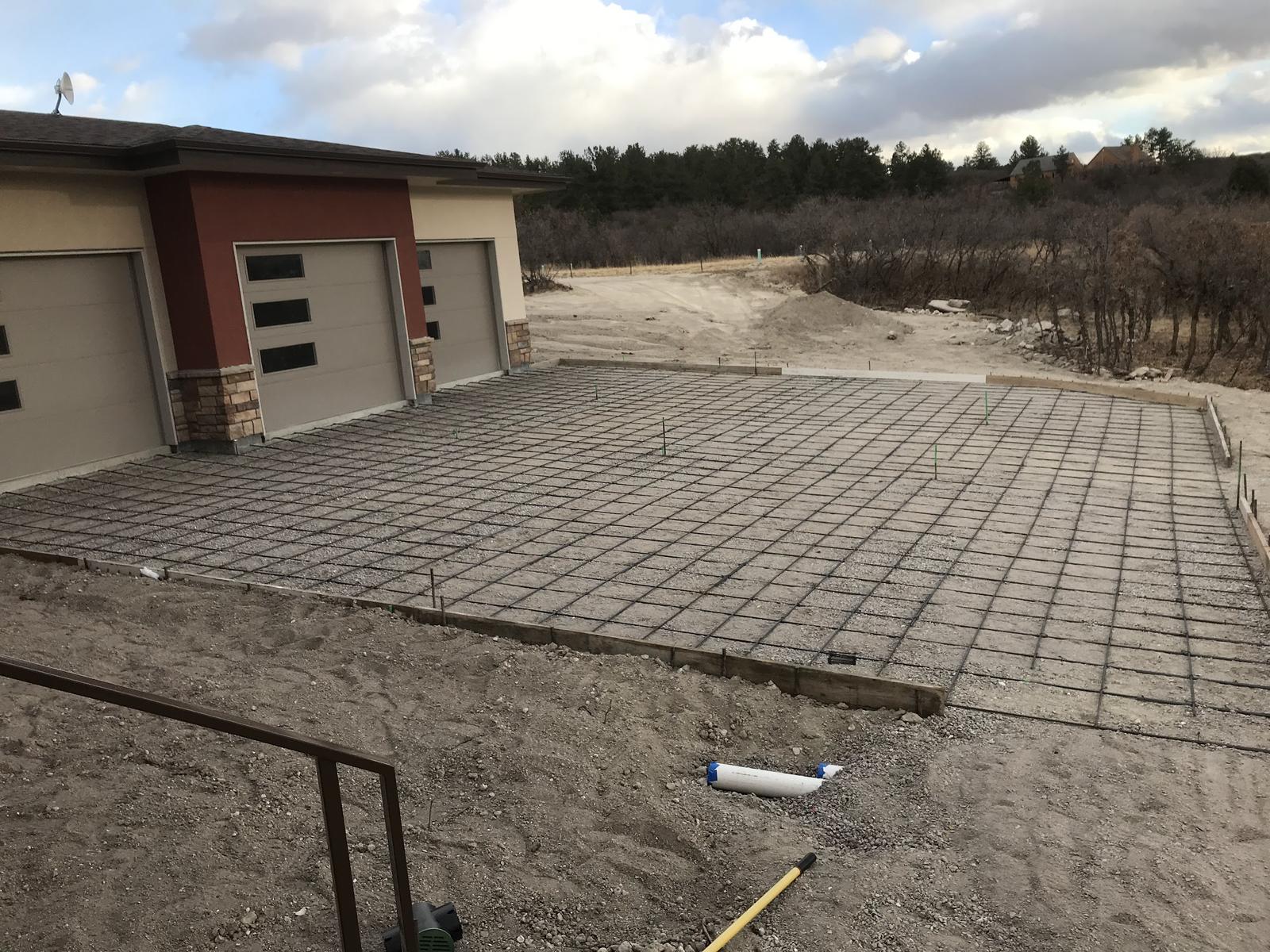 A large slab area formed and laid with steel reinforcement in front of a three-car garage, ready for concrete