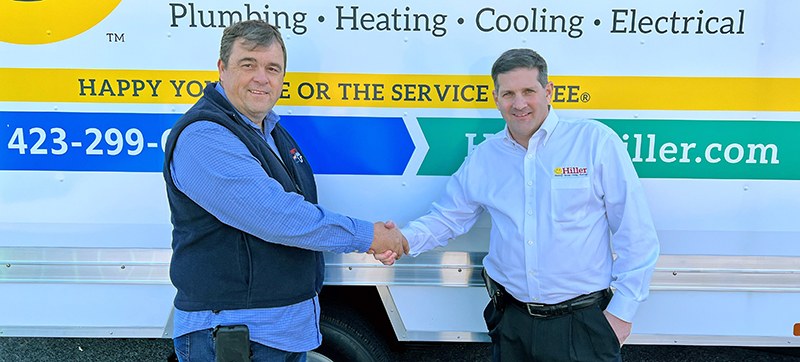 Jimmy Hiller in a white shirt shakes hands with another man in front of a white Hiller truck lettered with the company's trades and its satisfaction slogan
