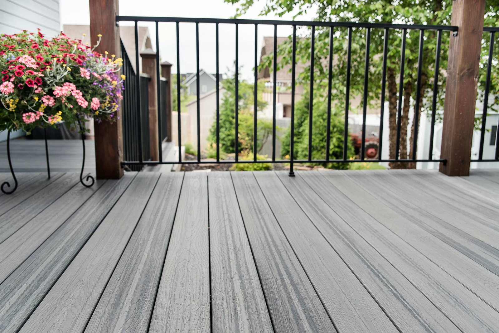 Gray composite decking boards with a black metal railing, wood posts and a hanging flower planter
