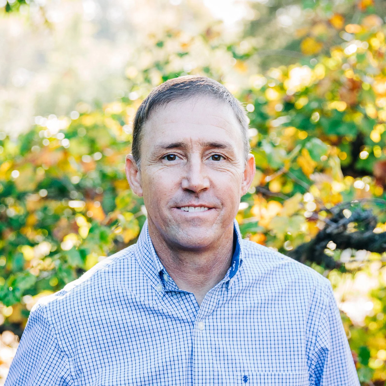 Bobby Oaks, owner of Oakes AC Services, smiling outdoors in a blue checked shirt