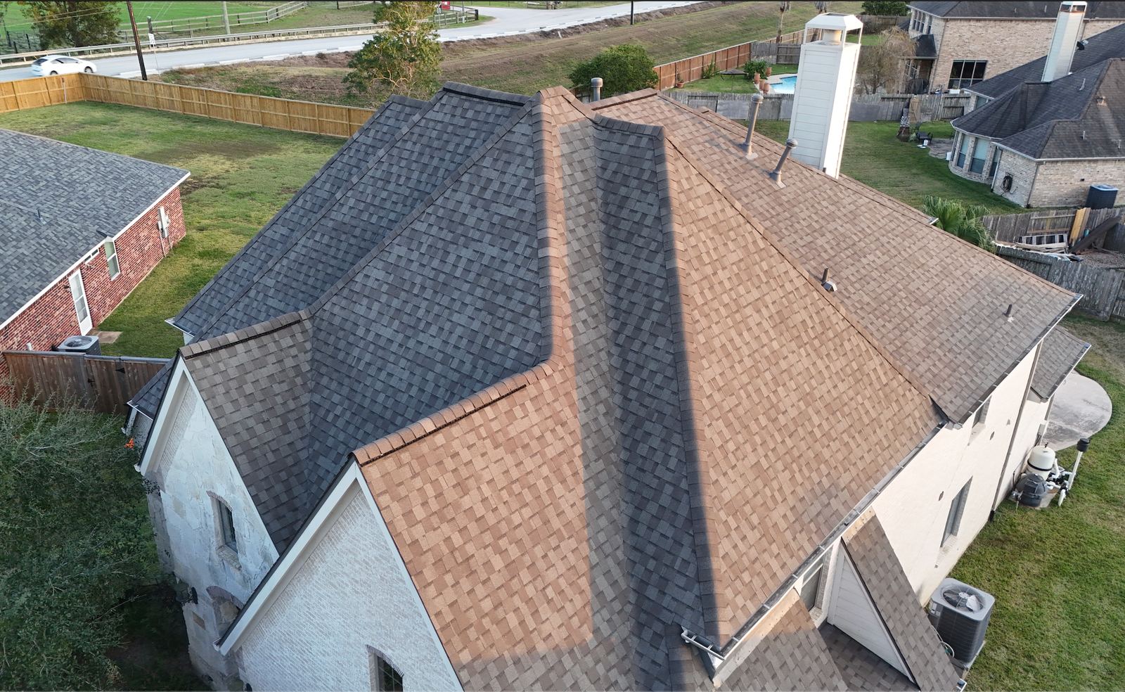 Drone view of a newly shingled roof with several ridges and roof vents on a two-story house