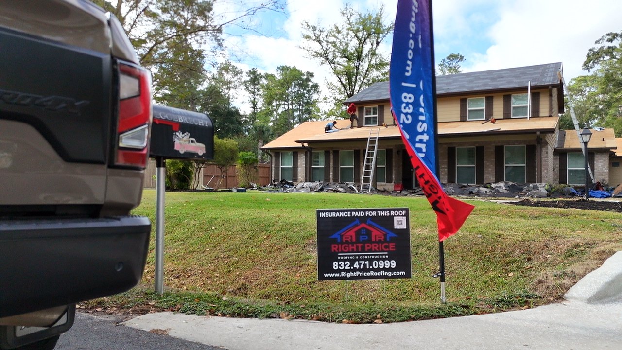 Right Price yard sign reading insurance paid for this roof in front of a home with crew on the roof and a company truck