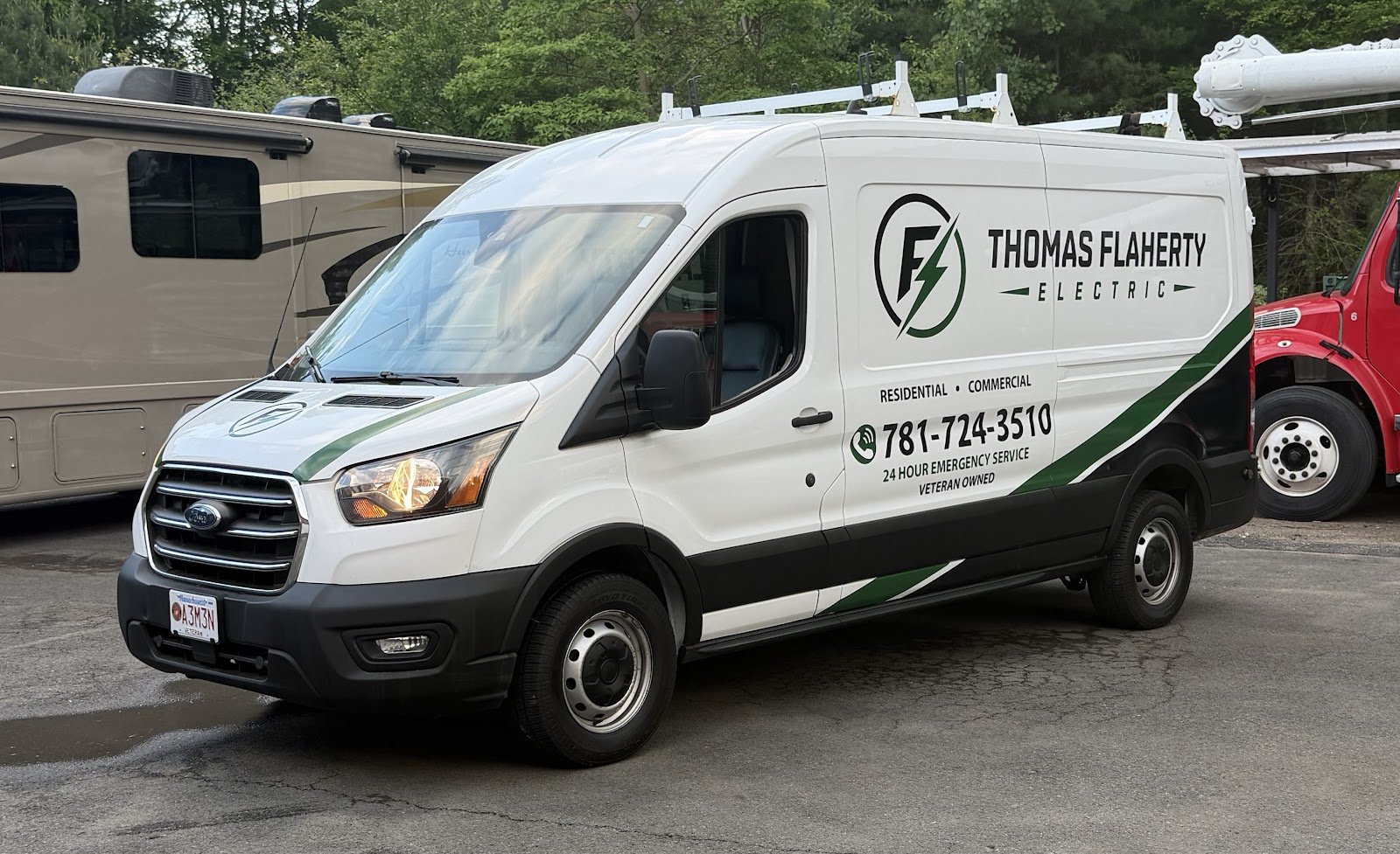 White Thomas Flaherty Electric work van with ladder racks parked on a paved lot, showing phone number and veteran owned lettering