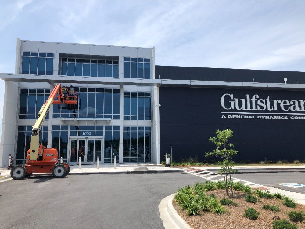 Worker in a boom lift cleans the upper windows of a modern two-story commercial building